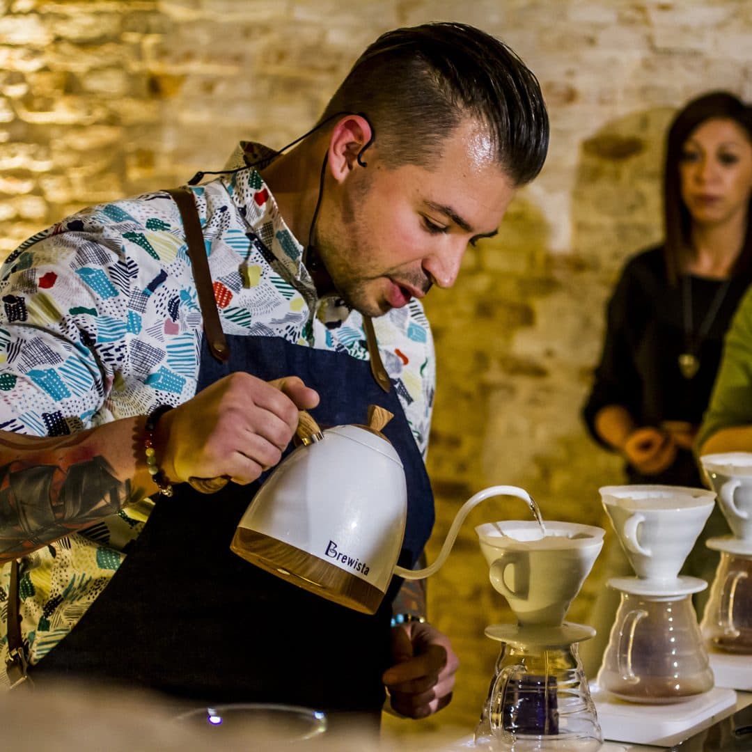 Alexandru Niculae, multiplu campion național la Brewers Cup, turnând apă în trei V60-uri în concurs