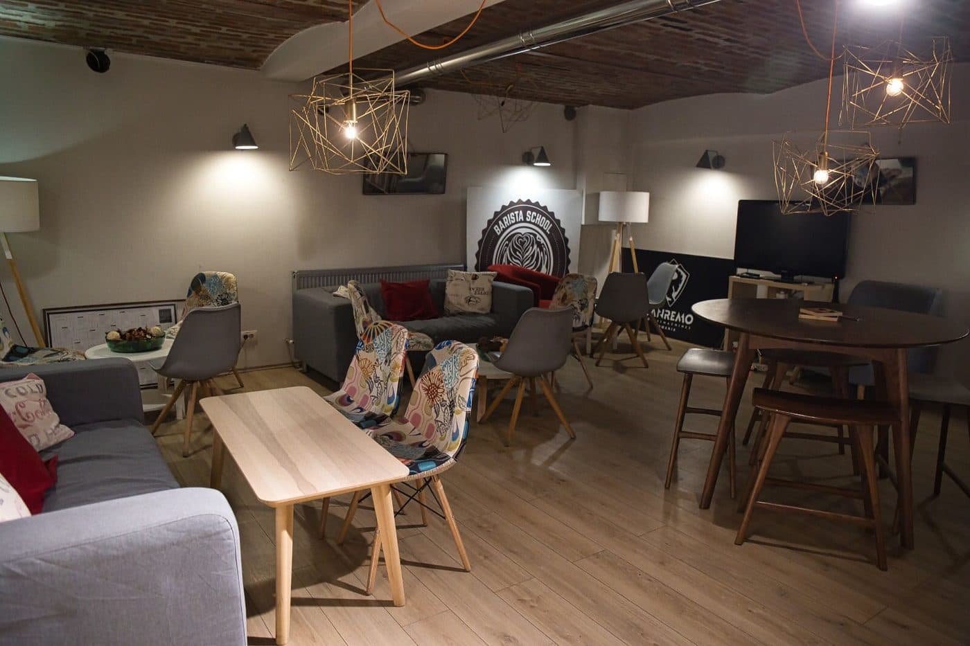 Sala Barista School din București, cu canapele, scaune și sigla școlii pe perete